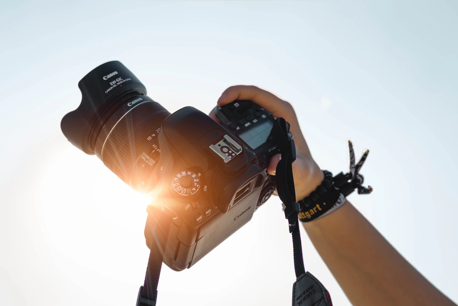 Fotocamera impugnata in controluce durante una ripresa al tramonto